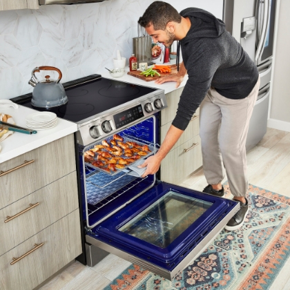 man taking out meat skewers from oven